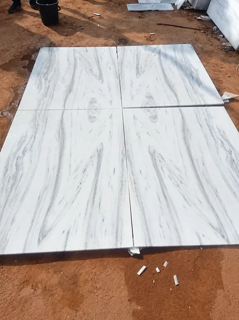 Veined white marble pieces laid out in the yard — enhanced business photograph